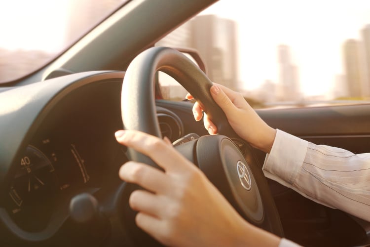 ハンドルを握って車を運転する人の手元
