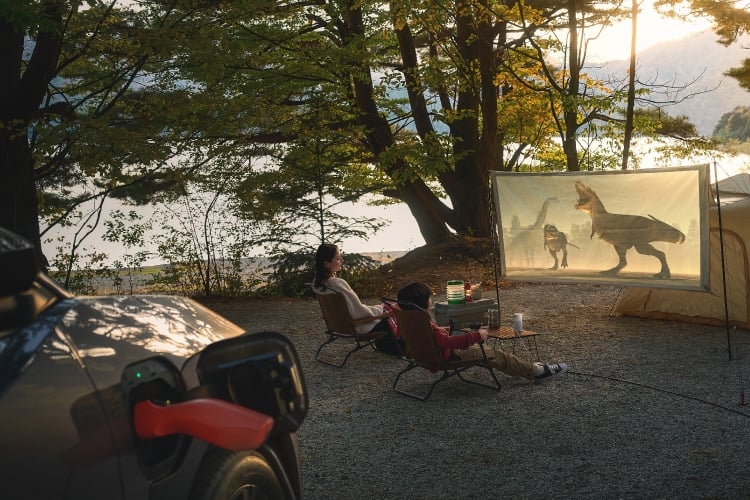 充電中のbZ4X Touring Z(4WD)を背景に屋外空間でスクリーン映画を楽しむ家族