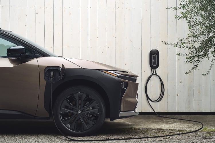 充電中(トヨタ6kW充電器使用イメージ)のbZ4X Touring Z(4WD)のサイドビュー。ボディカラーはクリスタルブラックシリカ×ブリリアントブロンズメタリック(メーカーオプション)。