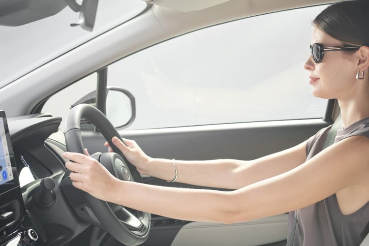 運転席でステアリングホイールを握るスタイリッシュな女性